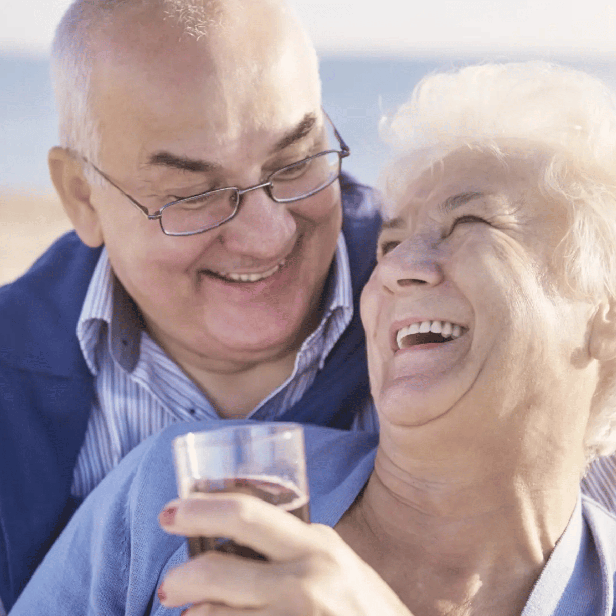 Pareja de adultos mayores sonriendo junto al mar